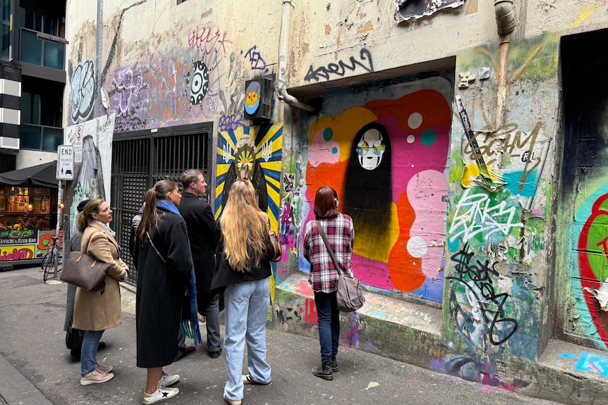 A group of people looking at street art