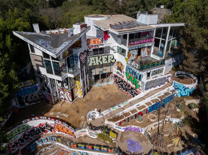 In an aerial view, workers paint the second of two mansions covered with graffiti in Los Angeles.