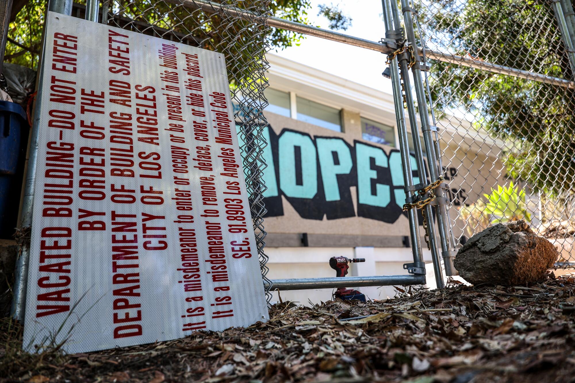 A sign saying vacated building - do not enter sits next to a fence under construction near graffitied walls of a mansion