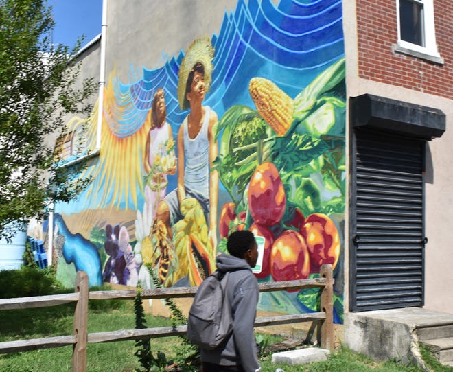 A student walks past a colorful mural on the 800 block of North 6th Street.