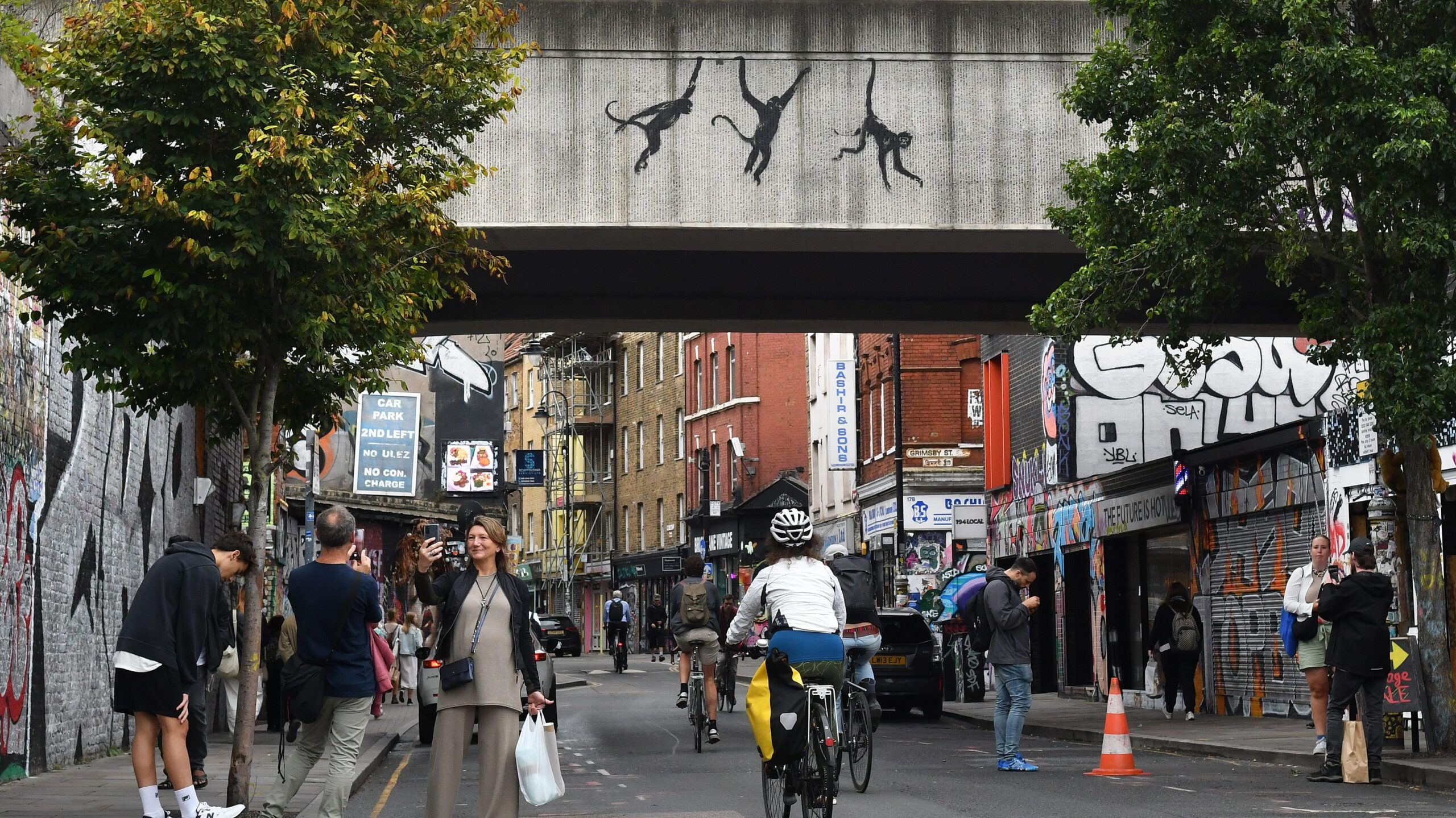 A Banksy painting shows three monkeys swinging from a bridge.