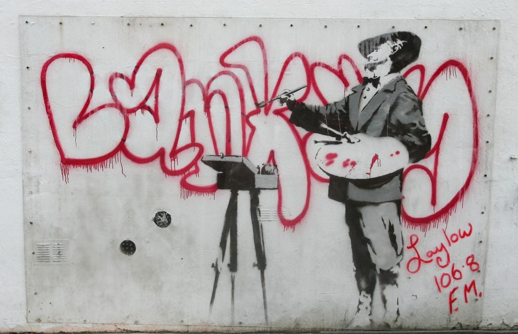 a graffiti sprayed on a wall shows an artist with his palette