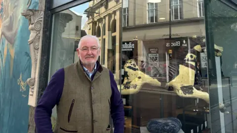 Keith Graham standing in front of his shop that has become victim to recurring graffiti tags