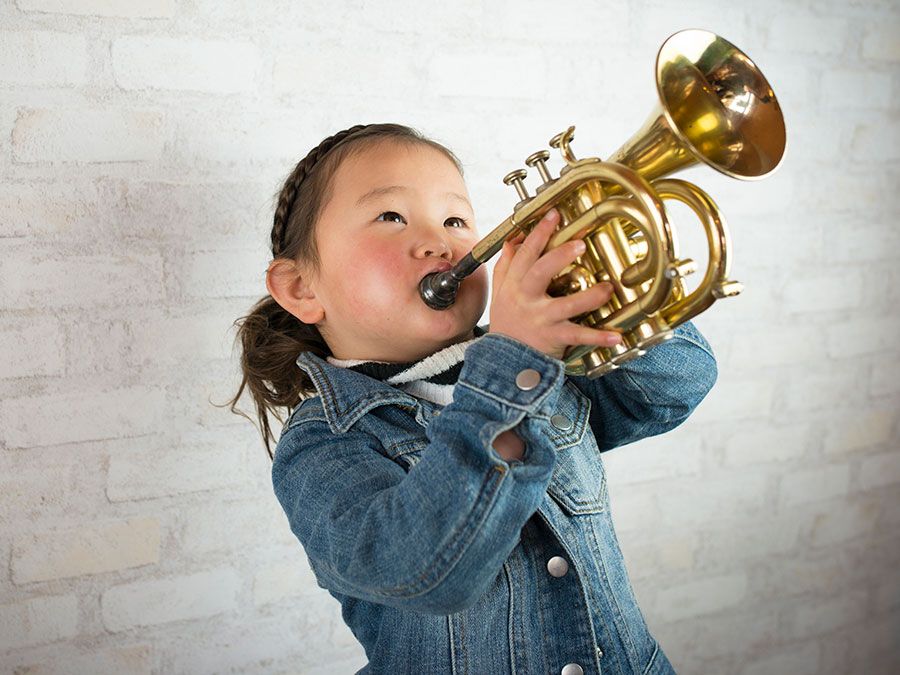 Young girl wearing a demin jacket playing the trumpet (child, musical instruments, Asian ethnicity)