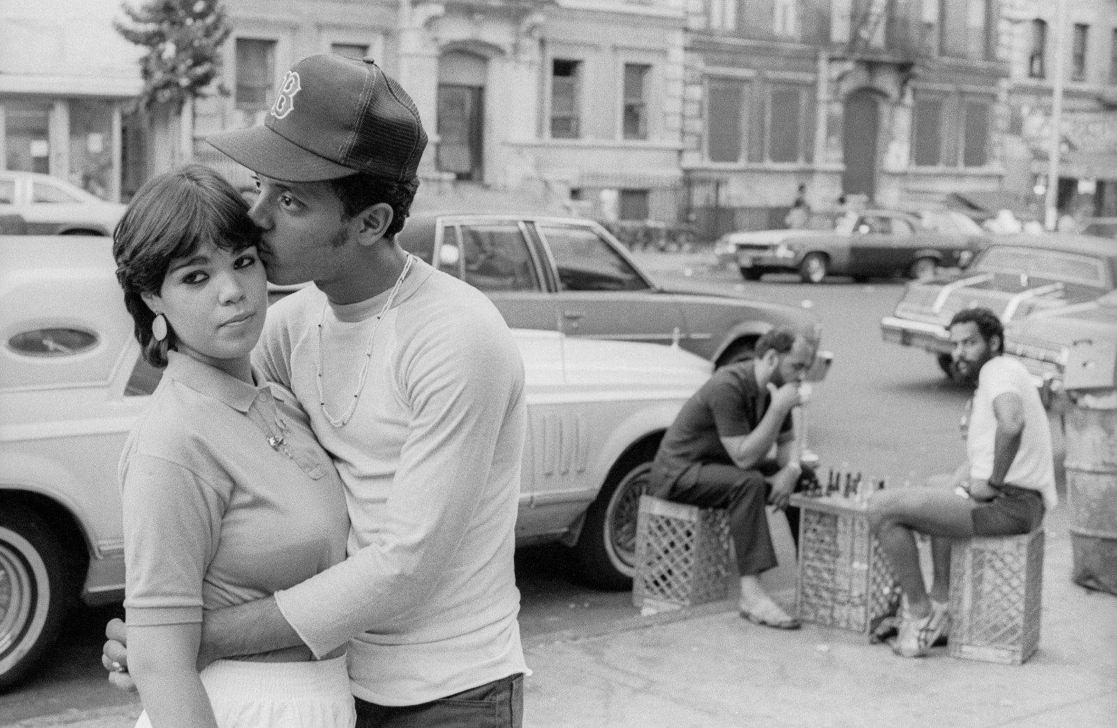 A man and woman embracing on the sidewalk.