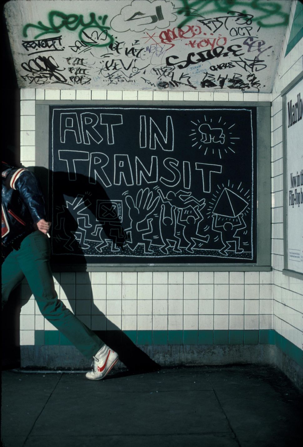 Image of half a body of a young man running after doing graffiti in the subway.