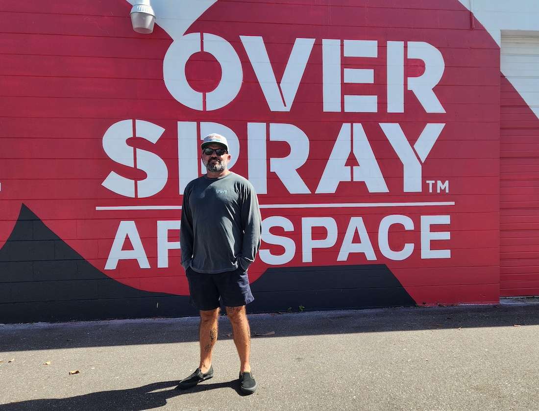 a man standing in front of a wall that reads 