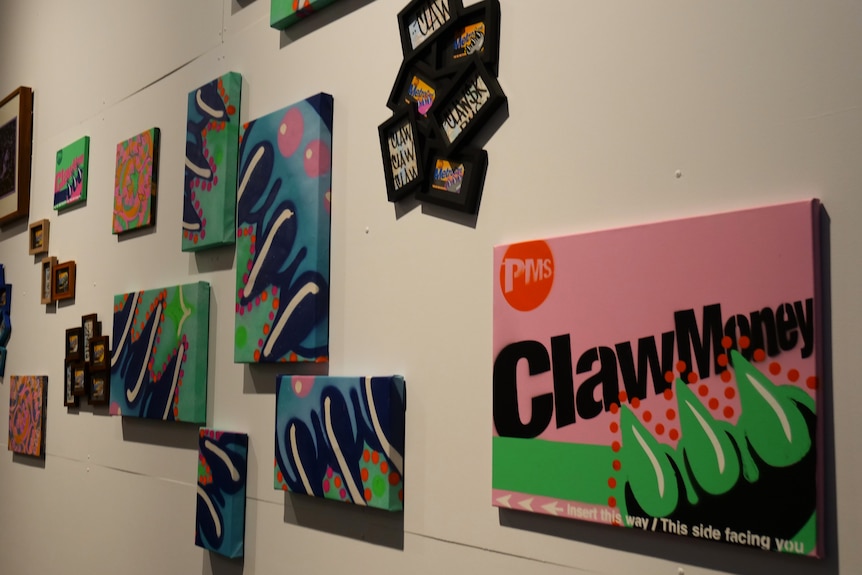 A collection of painted canvassed featuring a bubble style graffiti claw mounted on a white gallery wall.