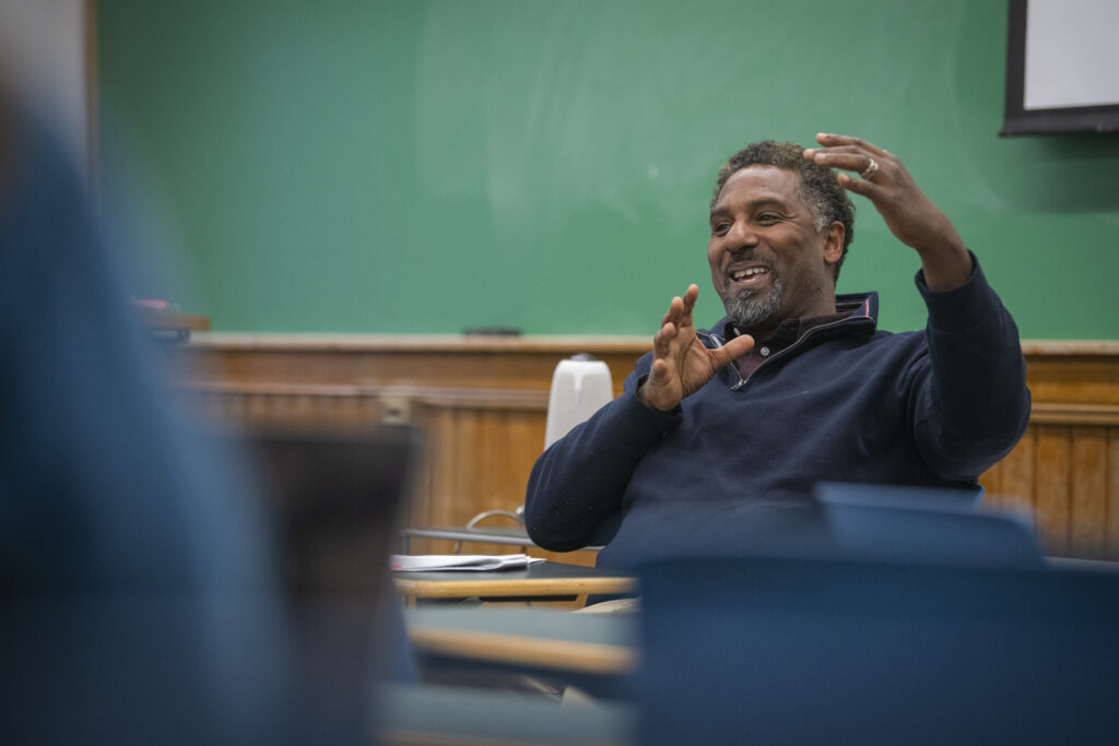 professor talks in front of green chalk board