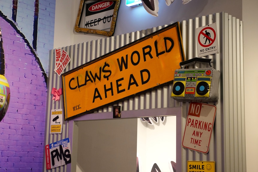 An array of classic New York City street signs mounted on corrugated steel create the entryway to one of the exhibit rooms