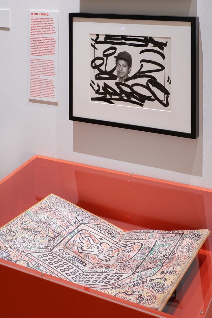 A Keith Haring book in a display case, opened to a page filled with doodles