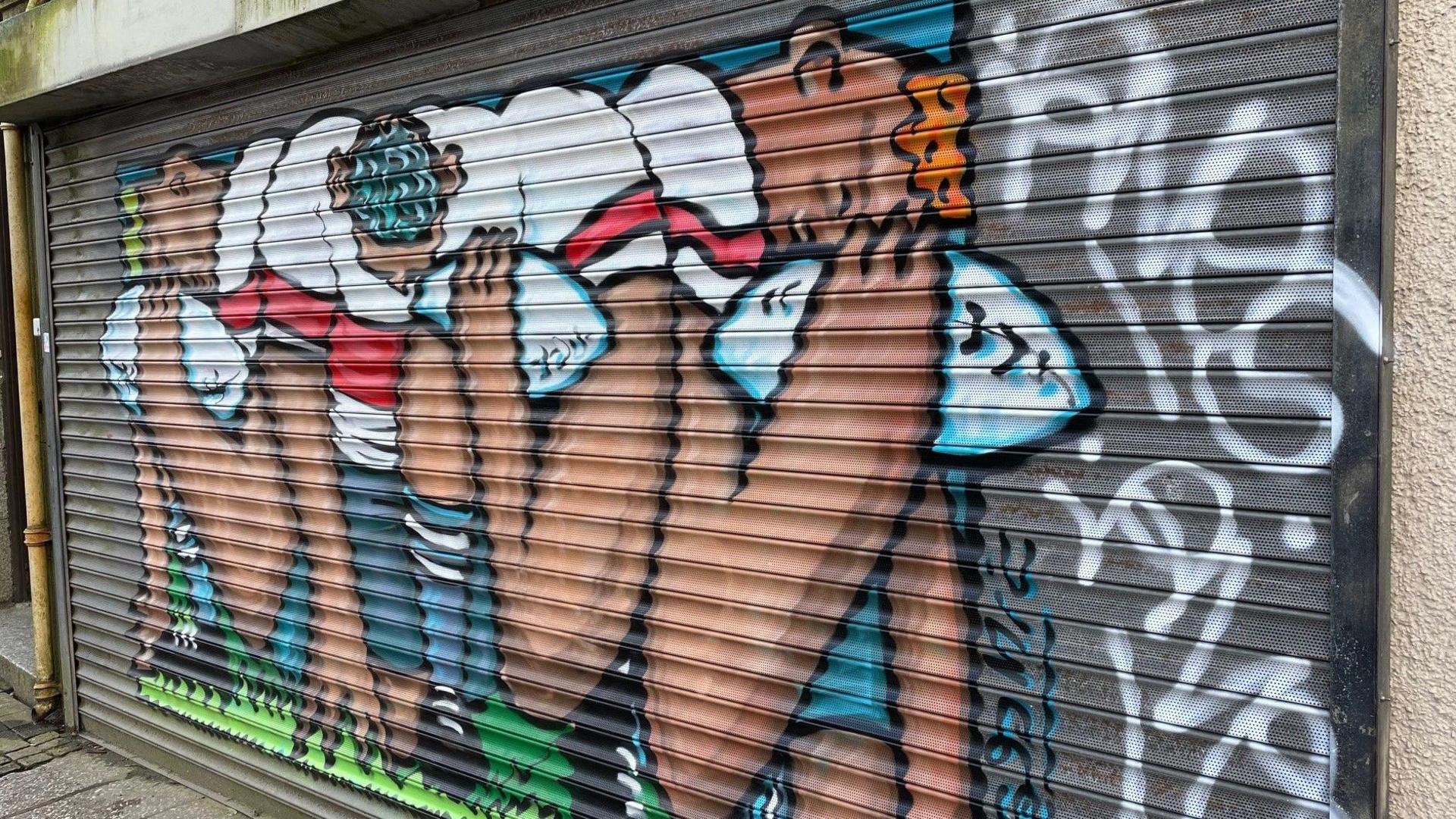 Mural on shutters with graffiti tags