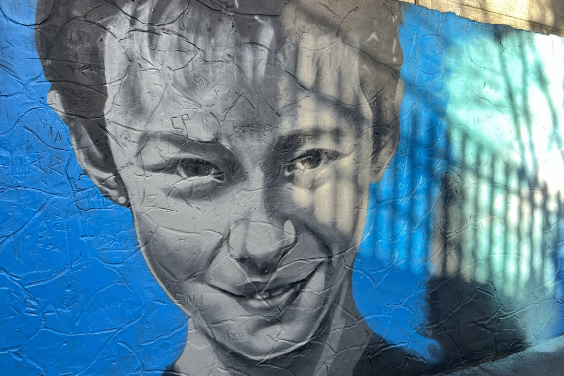 A close-up of Leo Ross's face painted on the mural, on a blue background. His face has been painted in black and white.