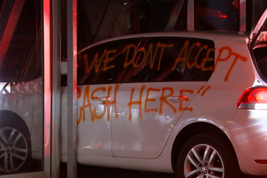 A car with graffiti in the front of a shop.