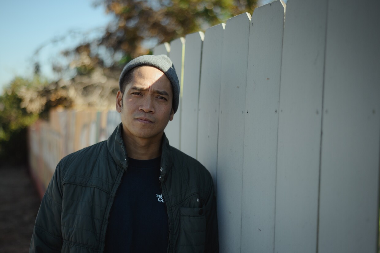 Romali Licudan, a tattoo artist and member of the old graffiti crew JVC, stands for a portrait in front of his new mural on Division Street in the Paradise Hills neighborhood of San Diego, California on December 18, 2024.