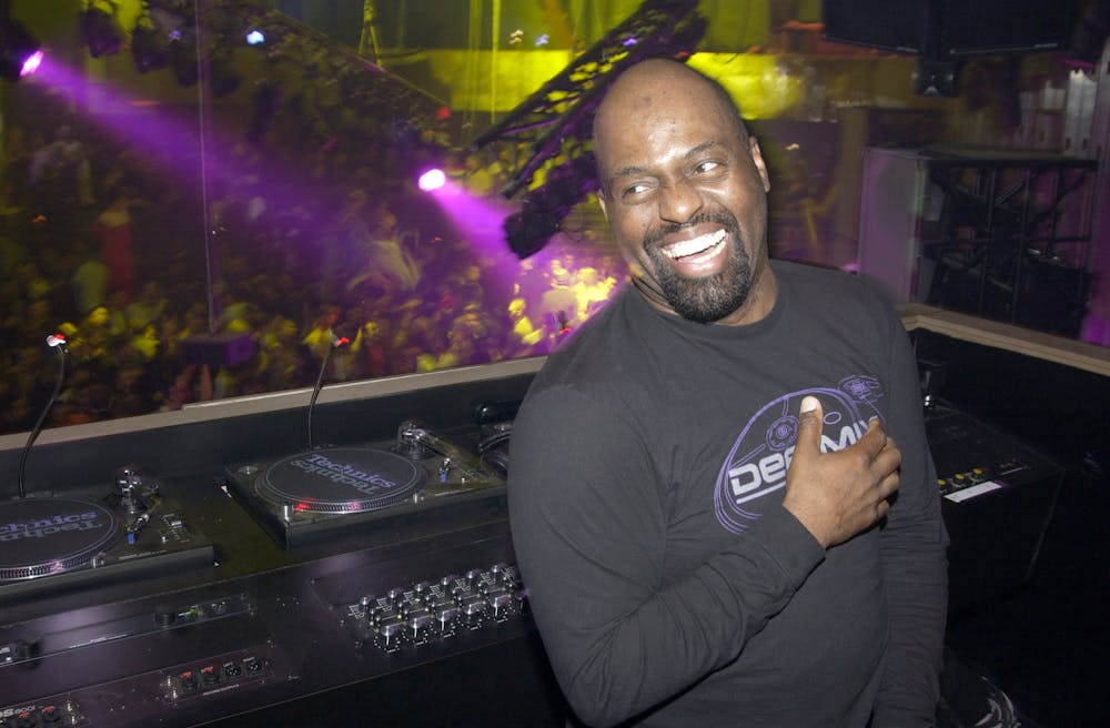 A man smiles in front of a DJ booth.