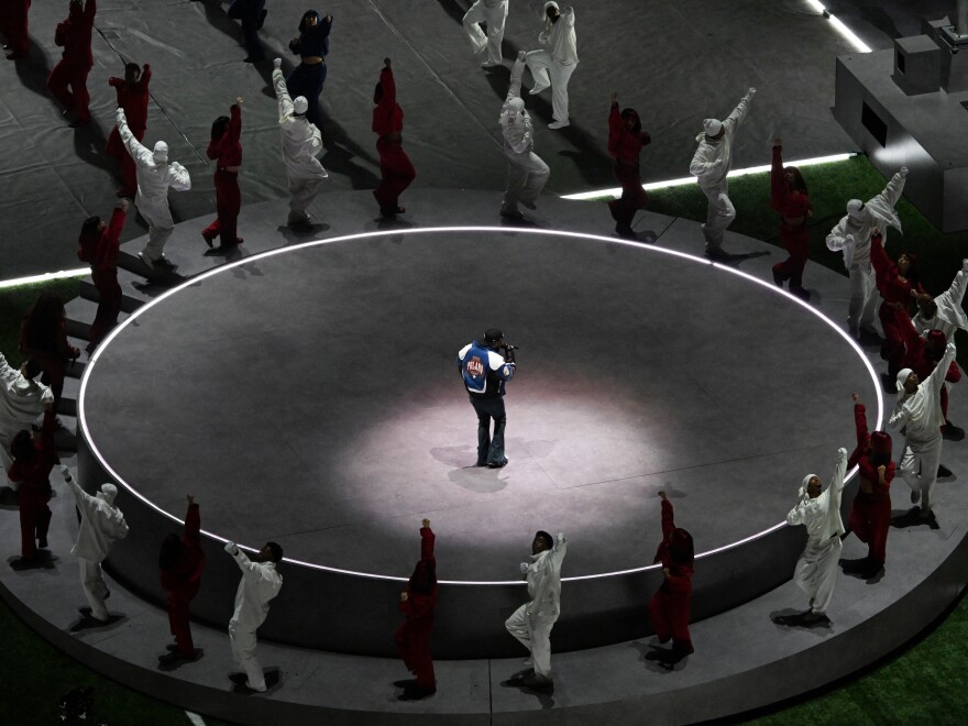 Kendrick Lamar performs on the center of an elevated circular stage surrounded by dancers during the Super Bowl LIX Chiefs vs Eagles Apple Music Halftime Show.