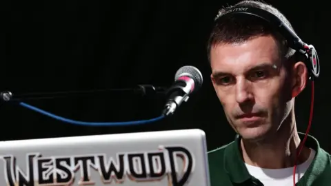 PA Media Tim Westwood pictured in 2014 DJing, using a laptop with his surname on it