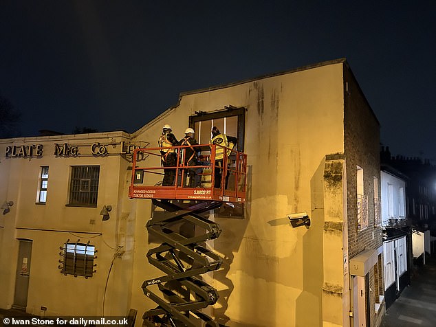 Builders were seen installing metal scaffolds around the section of the wall containing the artwork as they prepared to take it away