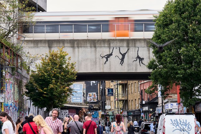 LONDON, ENGLAND - AUGUST 07: An artwork featuring three monkeys by Banksy, adorns a bridge over Brick Lane on August 07, 2024 of London, England. The elusive street artist posted a picture of the artwork earlier today on his Instagram account, his usual method of claiming credit. It came after he debuted two other works in London in as many days. (Photo by Aitor Alcalde/Getty Images)