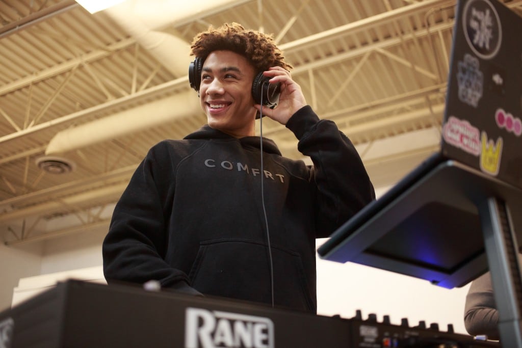 Jahleel Fisher stands in front of a sound mixer with a pair of headphones on.