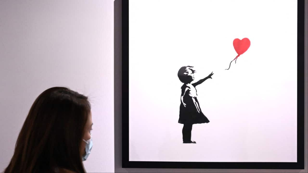 People view the art of Banksy, an England-based street artist, political activist, and film director. (Image credit: AFP)