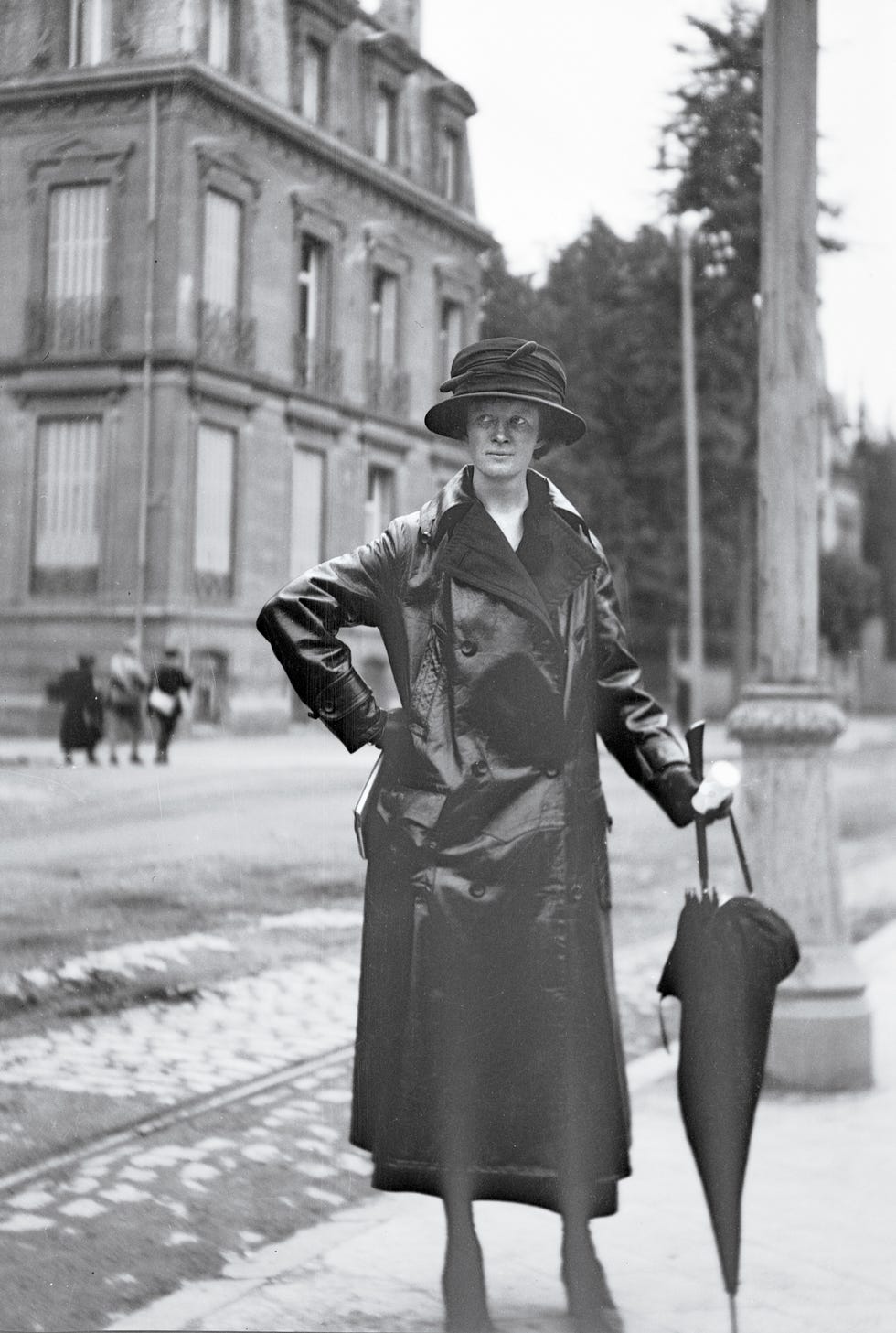 Person in a coat and hat holding an umbrella on a street.