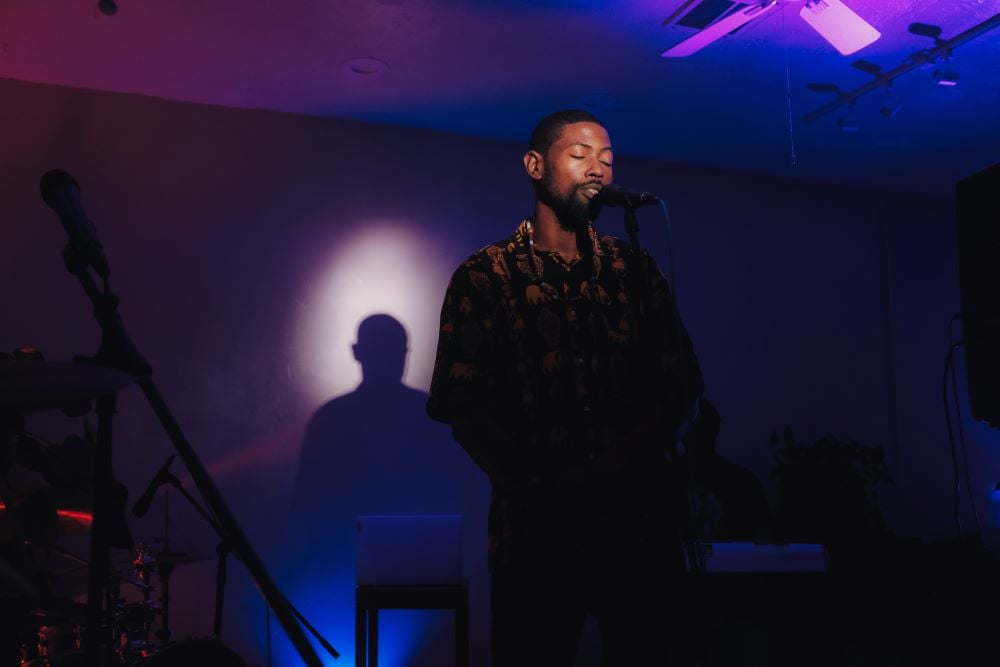 man on stage in front of mic with purple backdrop