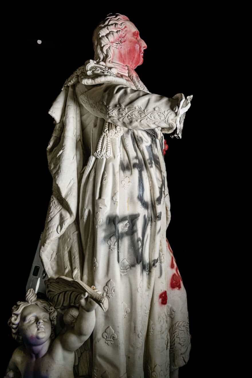 A side view of the Louis XVI statue with spray-painted graffiti