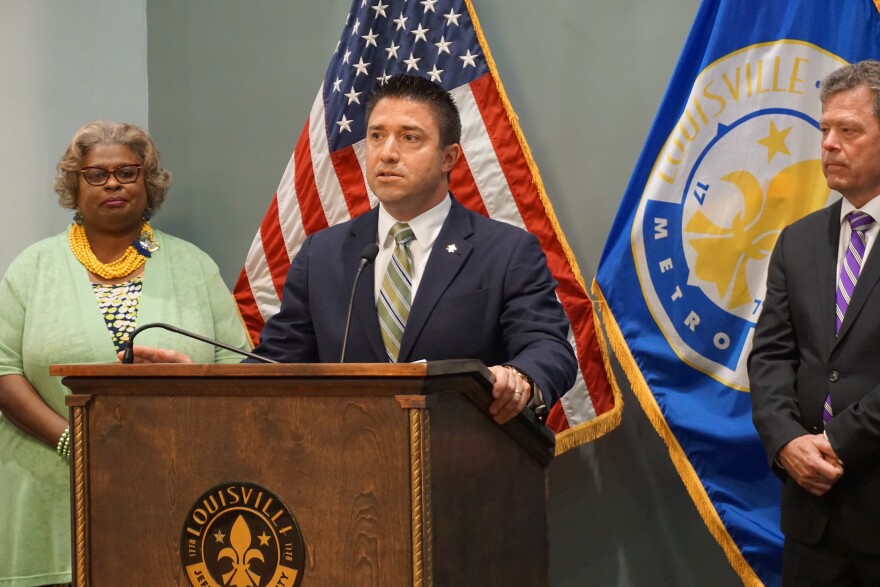 Metro Council member Anthony Piagentini at a lectern, with two people behind him