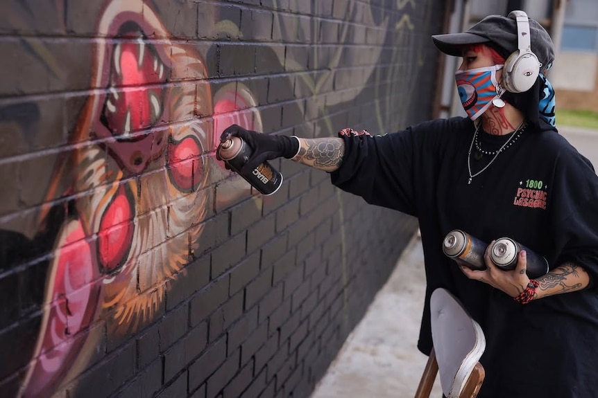 A graffiti artist spray painting a wall