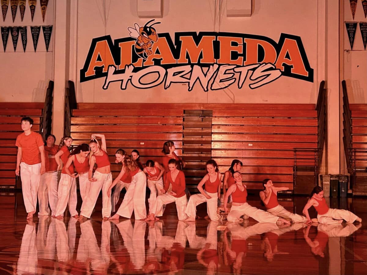 Alameda Post - dancers perform at the AHS gym in front of a wall that says