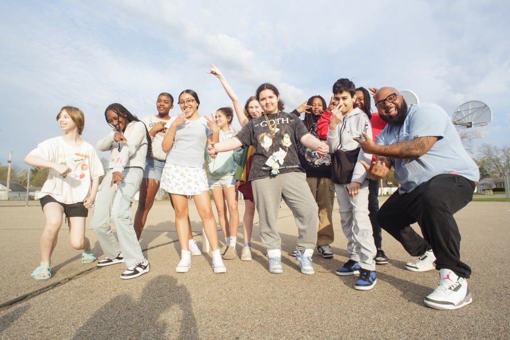 Trevon Hobson and ten middle schoolers pose on a basketball court.