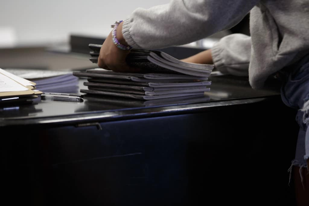 Trevon Hobson stacks composition books on a desk.