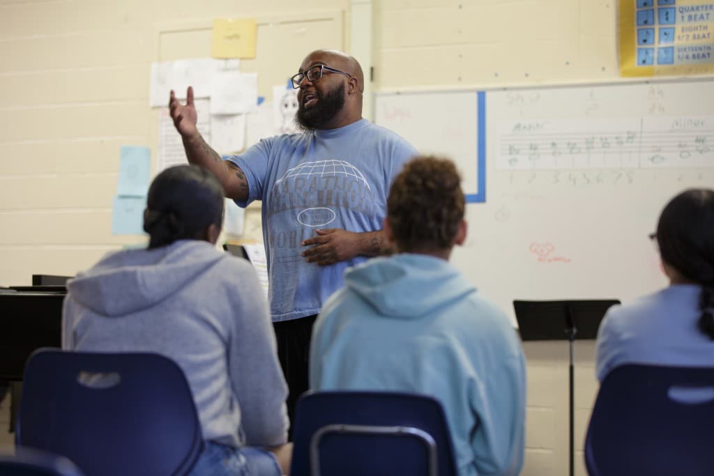 Trevon Hobson stands at the head of a classroom talking to a group of students.