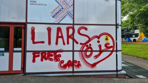 White panelled exterior wall of BBC Broadcasting Centre. Underneath the BBC Newcastle sign are the words