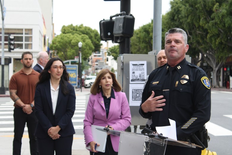 Press conference on a city street with community, police and attorneys regarding graffiti restoration fund.